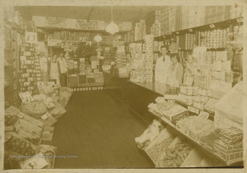 Two unidentified women and two unidentified men pose in the interior of a grocery shop.