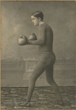 Portrait of Wright in stance with his boxing gloves. His weight, 178.