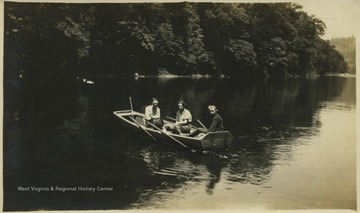 A boy and two girls float in their canoe on the river. 