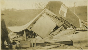 A man observes the destruction of an overturned house.