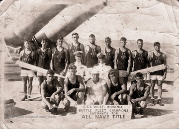 A group of men in swimsuits and holding oars pose together for a group photo. 