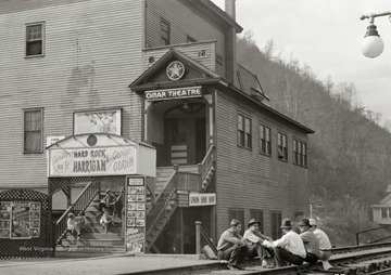 Several younger boys sit on steps leading up to the theatre.
