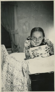 The girl in photo, "Jane', lounges in her parents bedroom, holding the novel, "Gone With the Wind". The book was authored by Margaret Mitchell and published in 1936. The movie was released in December, 1939. Immensely popular, the film won the Academy Award for Best Picture of the Year about the same time Jane was reading the novel.