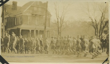 Uniformed men walk in formation across unoccupied streets.