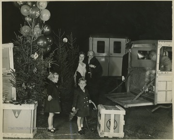 Photo description reads, "Peggy Ann and Peter Hoover, grandchildren of President and Mrs. Hoover, helping the packing of packages containing toys and other Christmas gifts for delivery to the poor little boys and girls of soft coal miners about Morgantown, W. Va., on the lawn of the white house on December 23. The children's mother, Mrs. Herbert Hoover, Jr., and the President's wife are looking on. The gifts were brought to the Christmas party of the children in the white house by the young sons and daughters of Washington's Officialdom."
