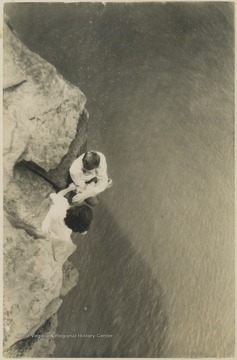 Two unidentified subjects climb along the rocks that tower above the river. 