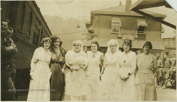 Group of women and nurses pose on the station platform. Subjects unidentified.