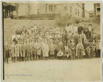 Group of unidentified men pose next to the station which is to the left of where the men are standing.