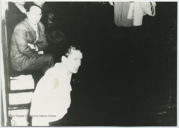 Close-up from the original photo showing men listen on as the Reverend speaks. 