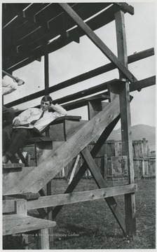 Labeled on back of photo is "Griffin", perhaps identifying the man leaning on the bleachers.