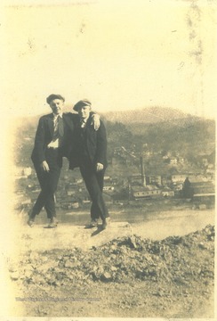 Two unidentified men pose with the town in the background. 