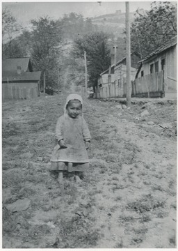 A young girl is pictured in a field between rows of houses. Subject unidentified.