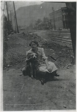 A girl poses with a dog by the railroad tracks. Subject unidentified. 