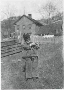 A young boy dressed as an Indian aims his toy pistol. Subject unidentified. 