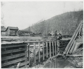 James Mill and pond pictured on the left. Two unidentified people sit along the bridge. 