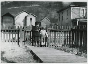 Two young boys pictured in front of a fence. The two-story house is catacorner to H&amp;N Ford Co.