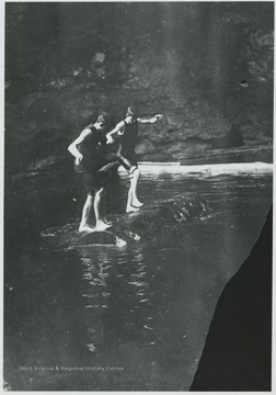 Two unidentified boys run on top of the turning log.