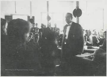 A man speaks to a crowded court room.
