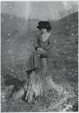 An unidentified woman is pictured sitting on a tree stump.