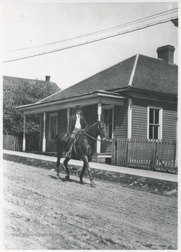 A man rides a horse through the street.