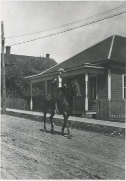 An unidentified man rides a horse through the street. 