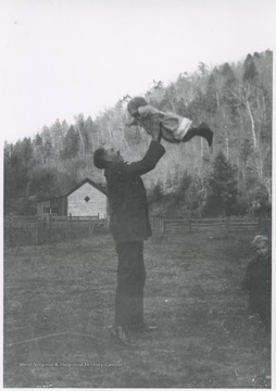 A man lifts a child in the air. Subjects unidentified. 