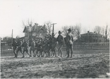 A group of enlisted soldiers run through a drill while supervised by a superior officer. Subjects unidentified. 