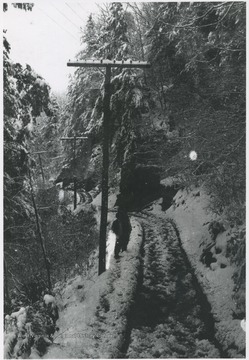 An unidentified man stands besides the snow covered tracks. 