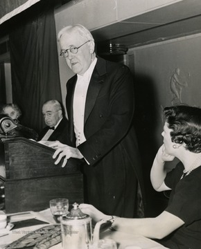 John W. Davis, chairman of the campaign, speaking at the dinner, in the Commodore Hotel, New York City, October 25th, that marked the opening of the Untied Hospital Campaign for Voluntary Hospitals. Miss Louise Iselin listens closely as Mr. Davis describes the needs of the hospitals to the 1,400 workers attending the dinner.