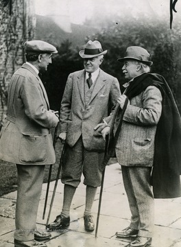 Caption on back of photograph reads: "A happy trio. Left to right: Earl Reading; United States Ambassador John W. Davis, and Premier David Lloyd George, of Great Britain. This exceptional photograph was made on the occasion of the Premier's first day in the country on his recent short vacation. Earl Reading, apparently, is telling a humorous story."
