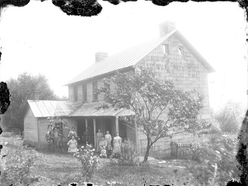 Young man behind seated woman appears to be holding a gourd while the man next to him holds onto what appears to be corn stalks.