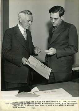 Inscribed on the back of the photo, 'Senator Rush D. Holt buys a peace bond from Frederick J. Libby, Executive Secretary of the National Council for Prevention of War, which launched a million dollar issue of peace bonds to build a more adequate American peace movement.'