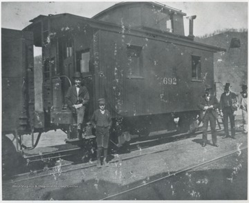 Men and a younger boy pose by the caboose car. Subjects unidentified. 