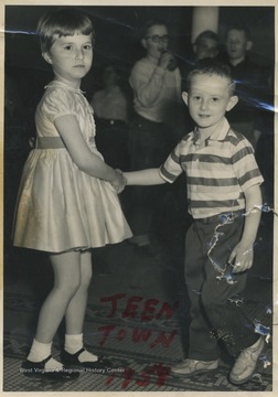 Two unidentified children are pictured holding  hands at a local hangout on 2nd Avenue. 