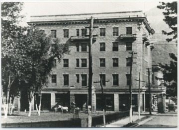 View of the building from down the street. A horse drawn carriage are pictured outside. 