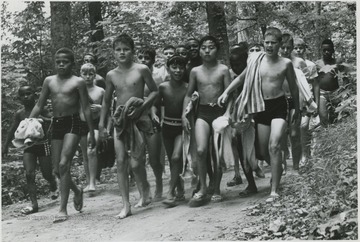 A group of young boys in their swim suits walk along the dirt trail. Subjects unidentified. 