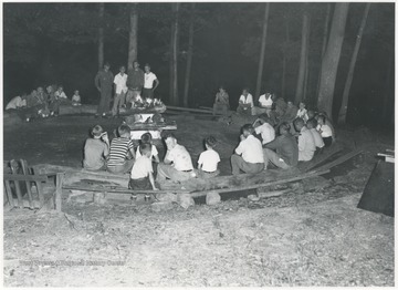 A group of young boys and their counselors sit around the campfire on the camp grounds located near Hinton, W. Va. 