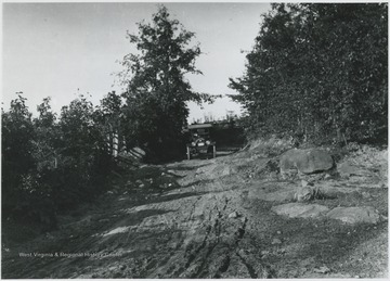 An old-fashioned automobile makes its way down the steep, dirt path. 