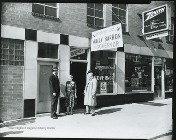A sign above the entrance reads, "Democratic Hdqs. for Wally Barron for Governor". Richard Baylor pictured on the far left speaking to an unidentified couple. 