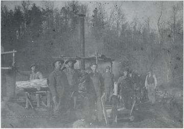A group of unidentified workers pose by the mill and their freshly cut wood planks. 