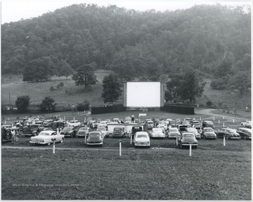 Rows of cars are parked along the field, prepared to watch the motion film.