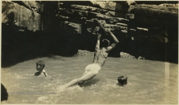 Three unidentified campers are pictured swimming in a watering hole.