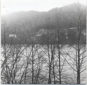 Looking through the trees at the flooded river almost reaching the houses on the hill. The river is either Greenbrier River or New River. 