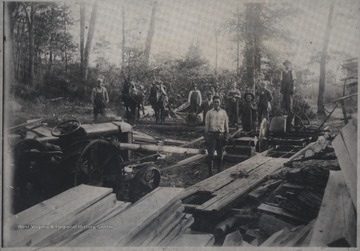 Employees and horses pictured beside the pile of lumber. 