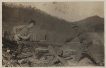 Two unidentified men take each handle of a saw and cut through wood. The farm is located by the mouth of Bluestone River. 