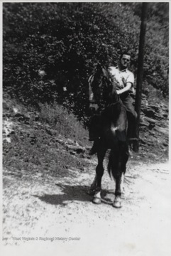 Martin sitting on top of a horse as they travel across the dirt path. Martin was a soldier during World War II.