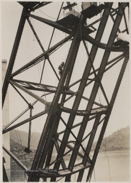 An unidentified man climbs up the collapsed structure.A week after the collapse the men began dismantling the twisted span, using a never before used technique by burning the steel beams with chemicals.Five workmen killed and four injured when the 300-ton span buckled and folded downward into the river. 