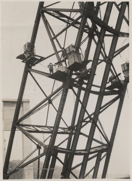 The men stand on the collapsed structure.A week after the collapse the men began dismantling the twisted span, using a never before used technique by burning the steel beams with chemicals.Five workmen killed and four injured when the 300-ton span buckled and folded downward into the mouth of Bluestone River. 
