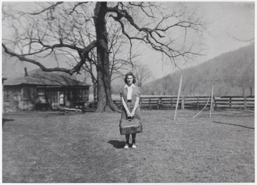 Neely holding a luggage bag in front of the farmhouse located near the mouth of Bluestone River. 