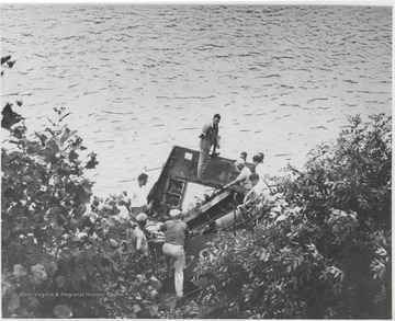 A group of unidentified men huddle around parts of the blown off engine where a handful of bodies were found. Among those killed were engineer W. H. Anderson, fireman J. W. Sullivan, and head brakeman O. L. Richmond.